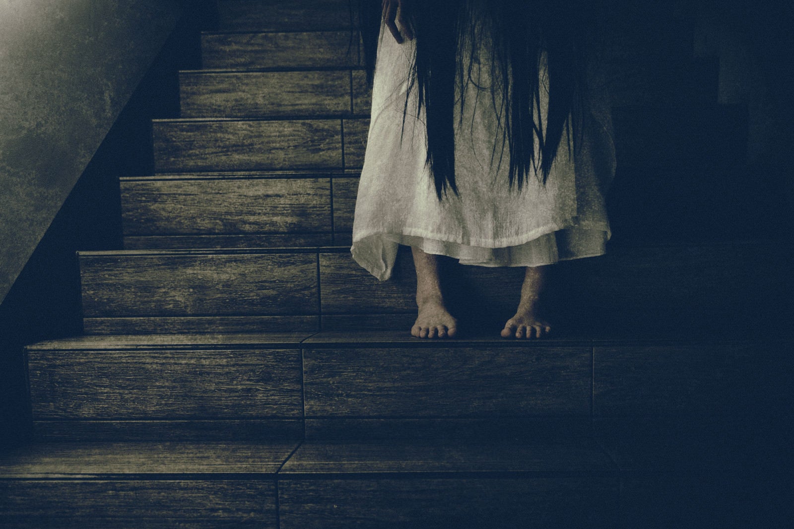 「薄暗い階段に佇む女性の足元」の写真［モデル：緋真煉］