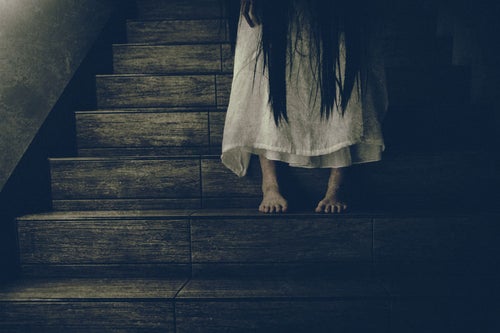 薄暗い階段に佇む女性の足元の写真