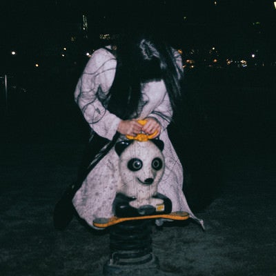 深夜の公園でパンダのスプリング遊具に乗った気味の悪い女性の写真