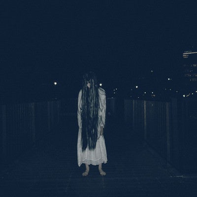 暗闇に立ちすくむ長髪の女性の写真