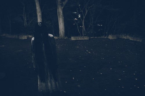 真夜中の広場で項垂れる白いワンピースの女性の写真