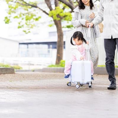 新緑の中を進む親子とキッズトラベルキャリーの写真