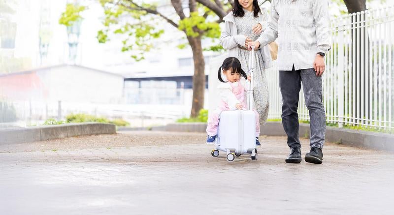 新緑の中を進む親子とキッズトラベルキャリーの写真