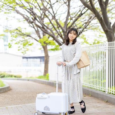 明るい雰囲気の中でキャリーケースを引く女性の春おでかけの写真