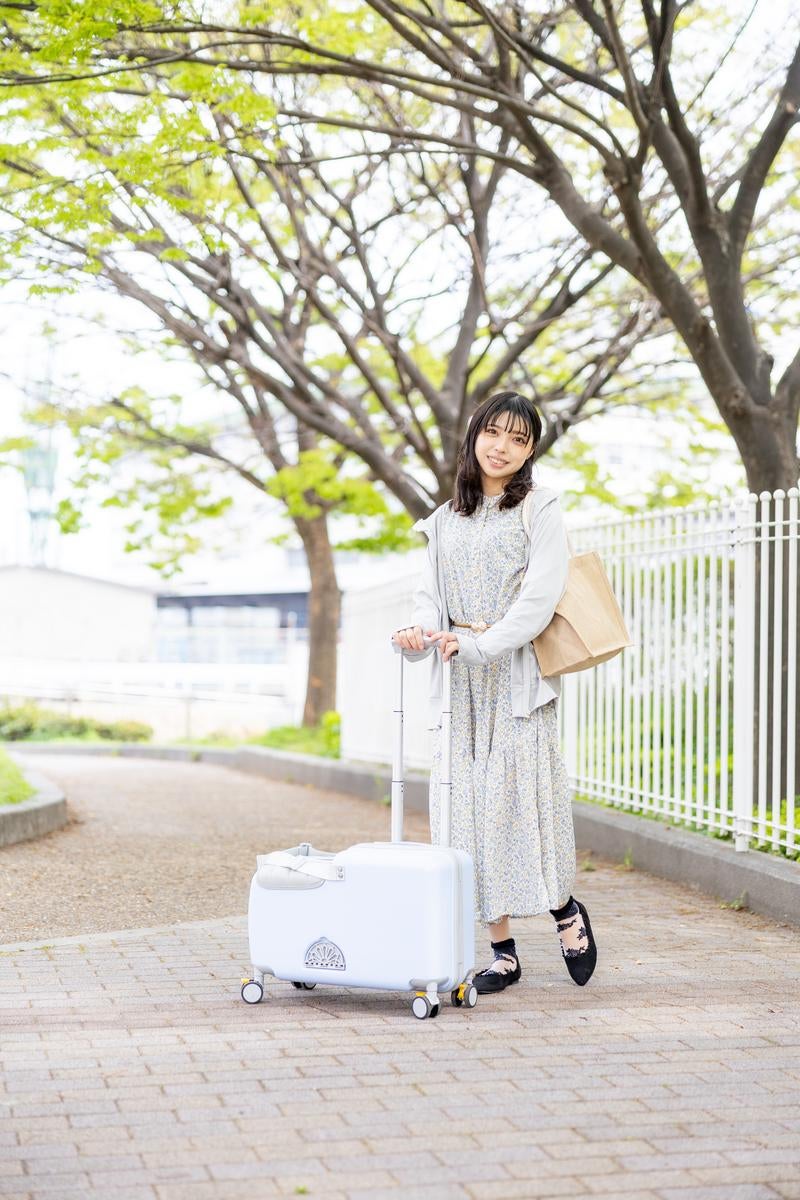 明るい雰囲気の中でキャリーケースを引く女性の春おでかけの写真