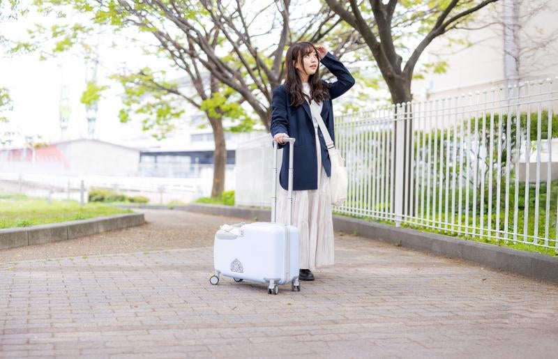 キャリーケースを持って目的地に向かう女性の写真