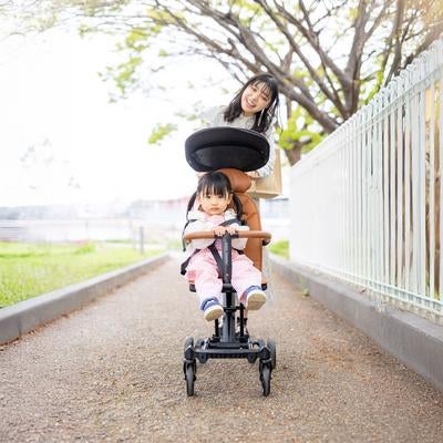 春の散歩道でベビーカーを押す親子のほほえましい日常の写真