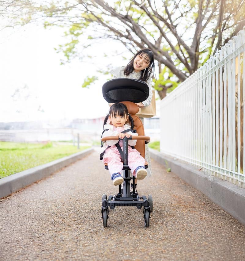 春の散歩道でベビーカーを押す親子のほほえましい日常の写真