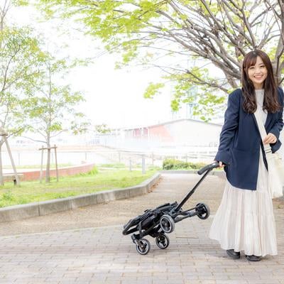 折りたたみベビーカーを持ち歩く女性の写真