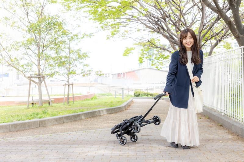 折りたたみベビーカーを持ち歩く女性の写真