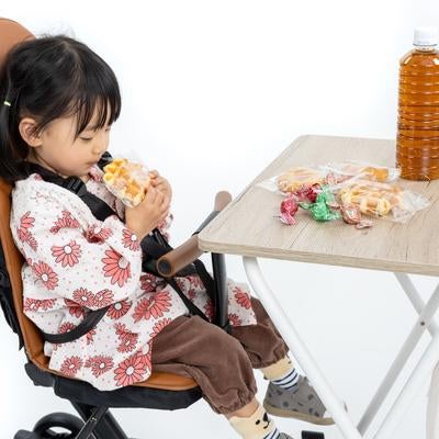 チャイルドチェア（ベビーカー）でおやつタイムを満喫する女の子の写真