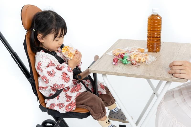 チャイルドチェア（ベビーカー）でおやつタイムを満喫する女の子の写真