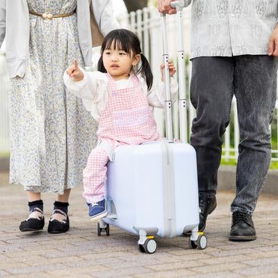 キャリーケースに乗って楽しく移動する子どもの写真