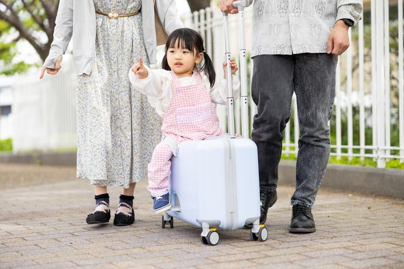 キャリーケースに乗って楽しく移動する子どもの写真