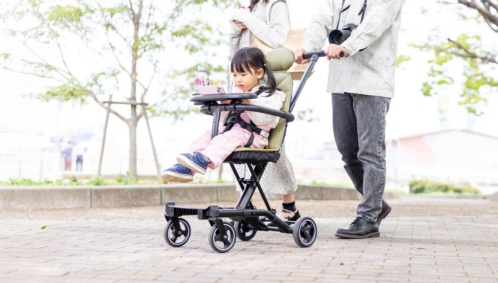 「ベビーカーに乗りながらスマホを見る女の子」の写真
