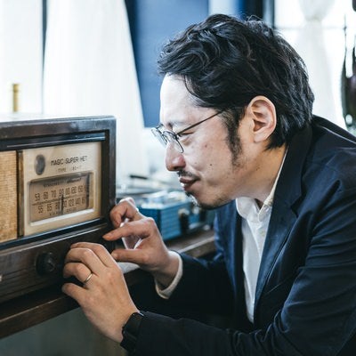 古いラジオのチャンネルを調整する男性の写真