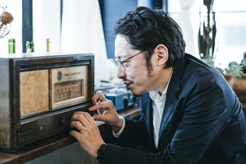 古いラジオのチャンネルを調整する男性の写真