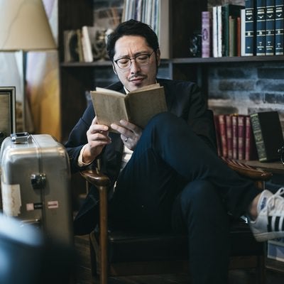 スーツケースと読書を楽しむ男性の写真