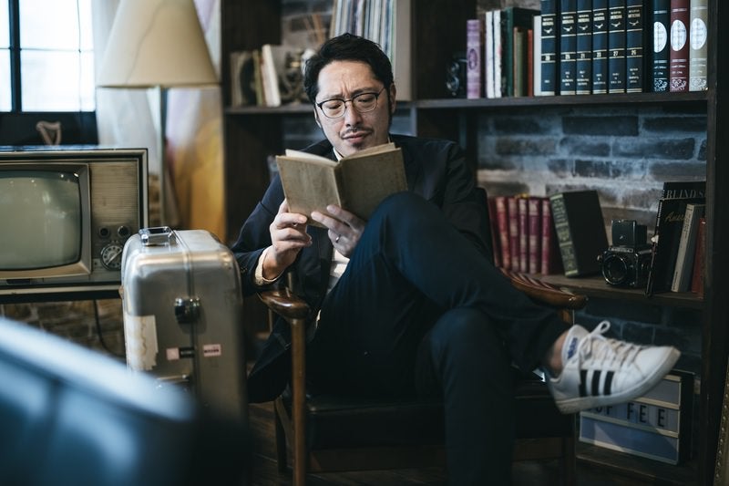スーツケースと読書を楽しむ男性の写真