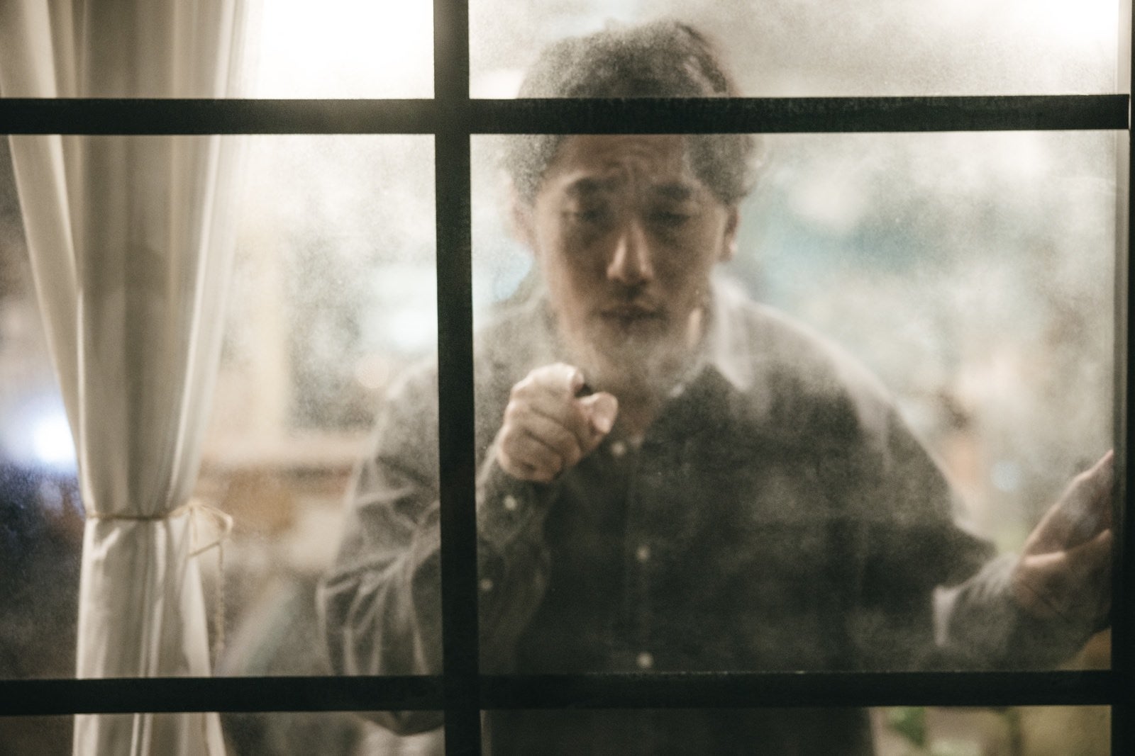 「曇ったガラスに指を差す男性」の写真［モデル：大川竜弥］
