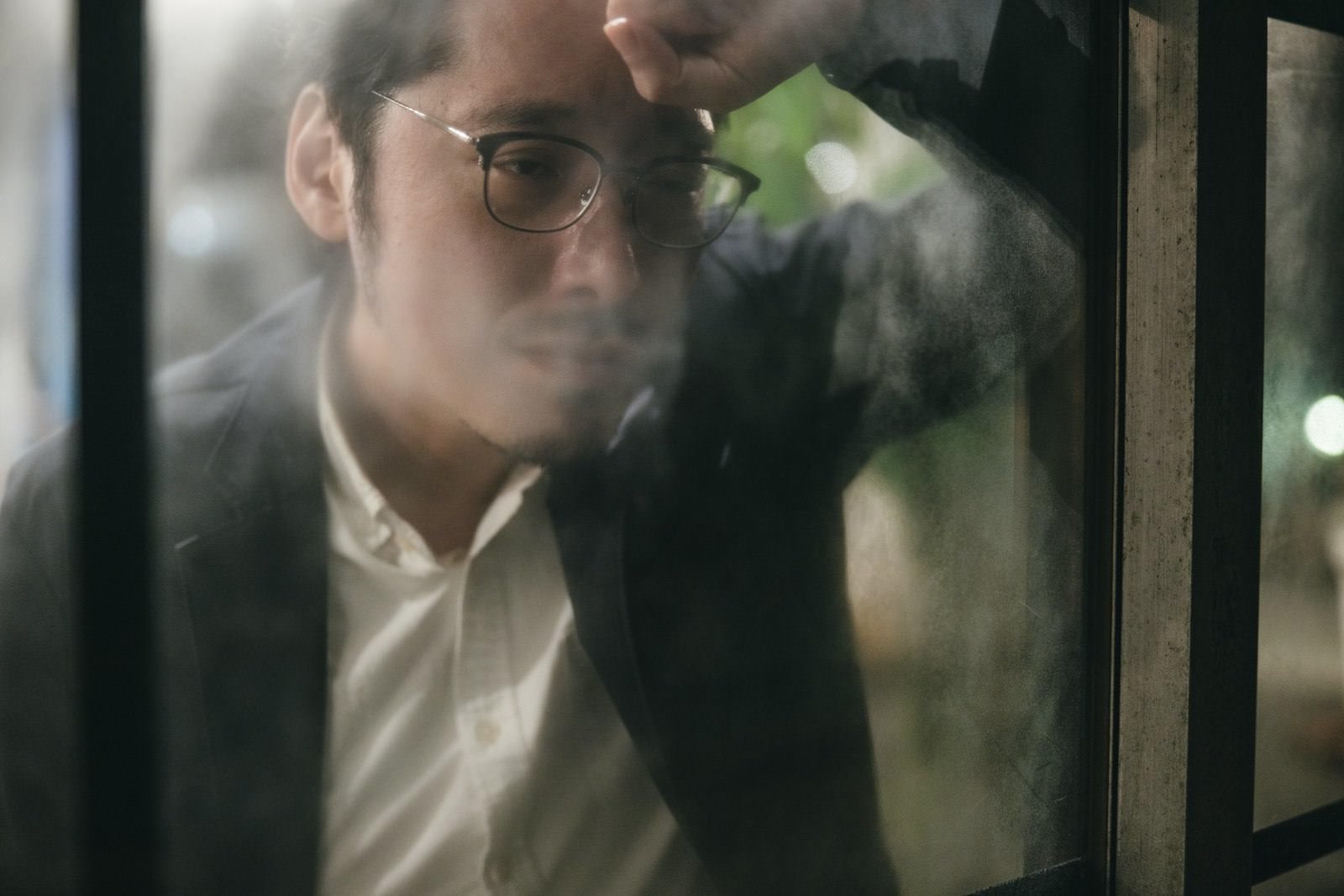 「窓の外を見ながら落胆する男性」の写真［モデル：ゆうせい］