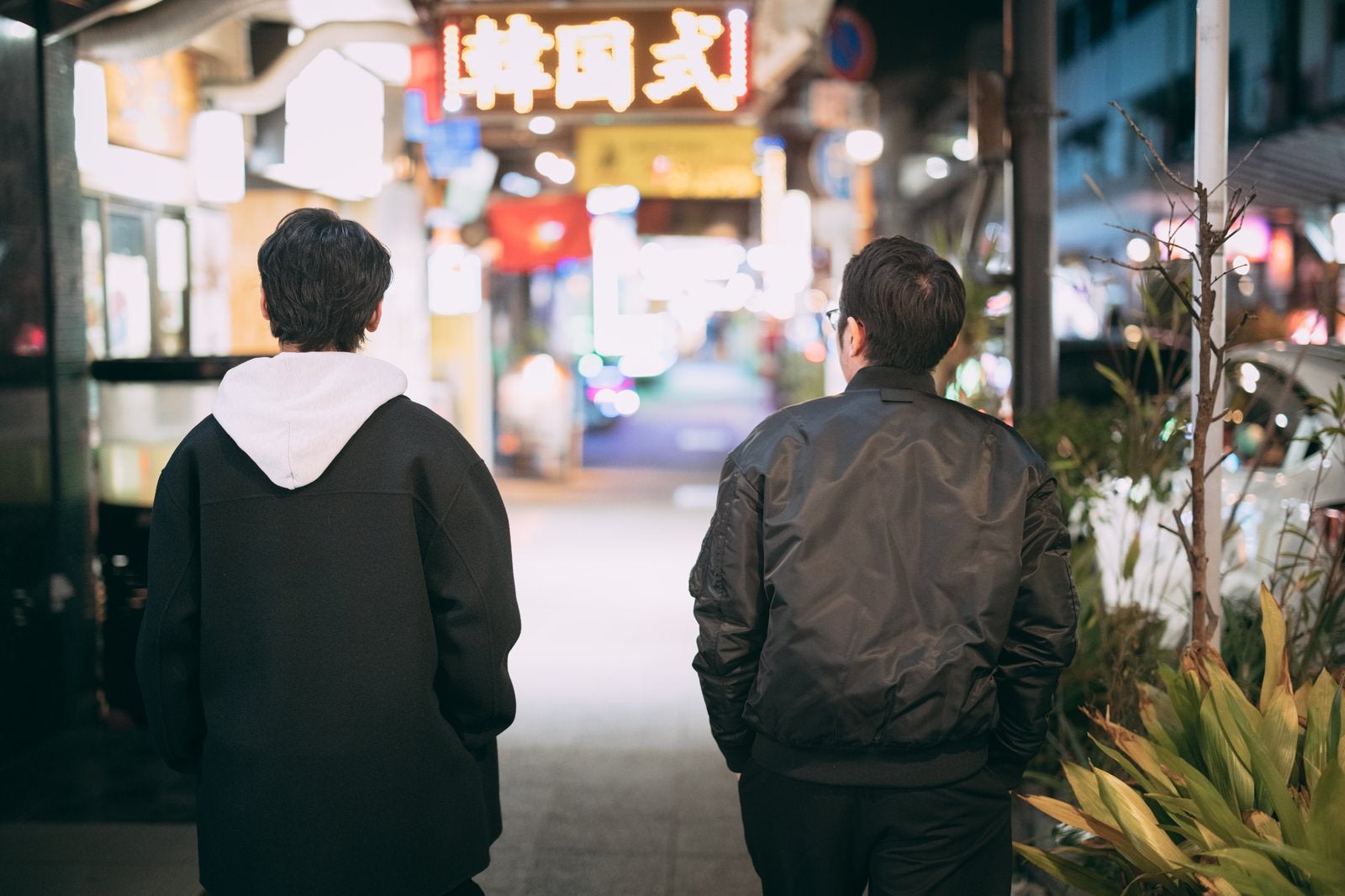 「ネオンが輝く繁華街を歩く男性ふたり」の写真［モデル：大川竜弥 ゆうせい］