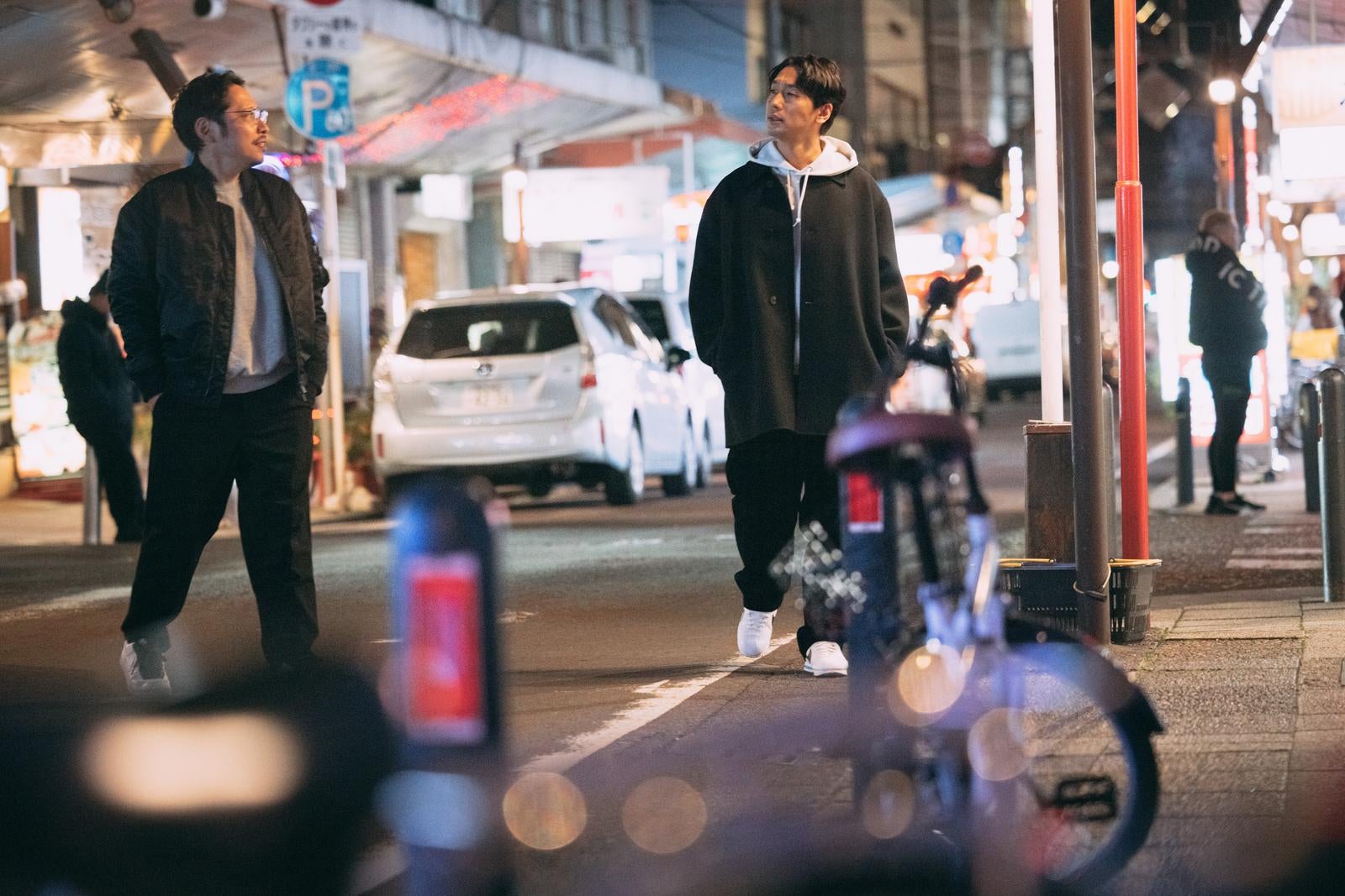 「夜の都会を散策する男性二人の自然な姿」の写真［モデル：大川竜弥 ゆうせい］