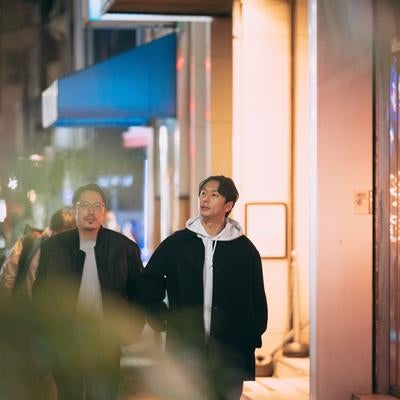リラックスして歩きながら会話を楽しむ二人の男性の写真