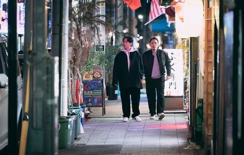 夜の繁華街を歩く探偵の二人組の写真
