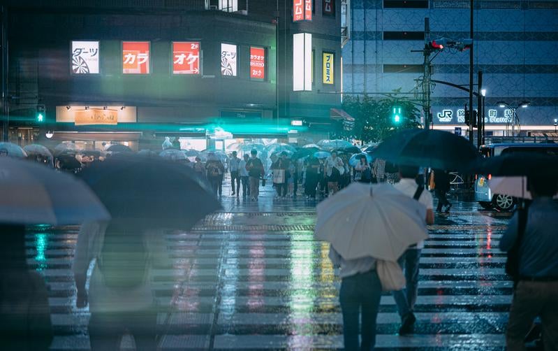 錦糸町駅の濡れた横断歩道と信号待ちする歩行者の写真