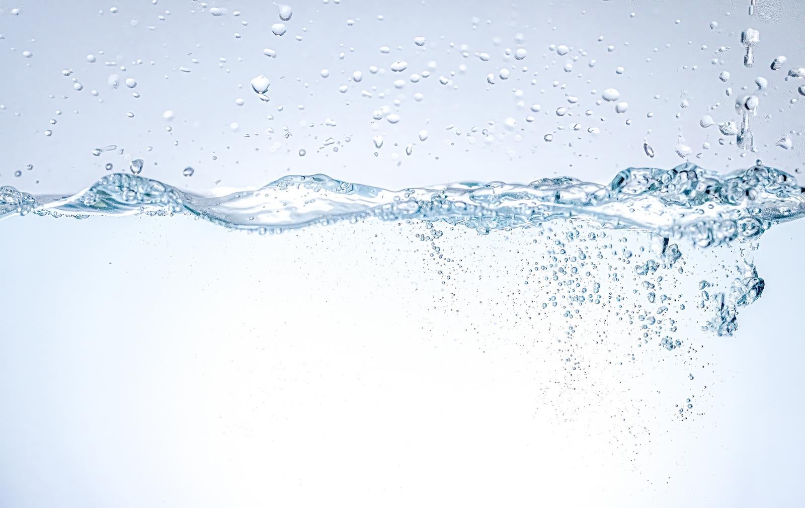 透明な水面に立つ波紋と水中に舞い散る無数の気泡