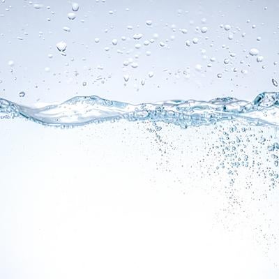 透明な水面から立ち上がる波紋と無数の気泡の写真