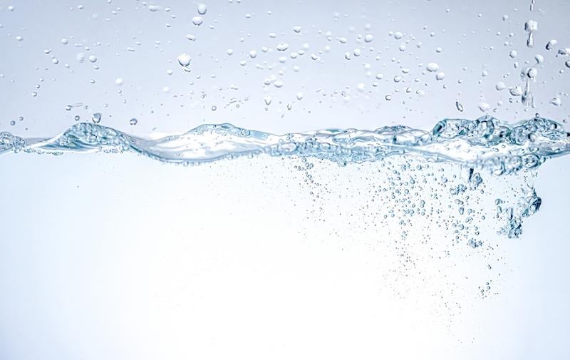 透明な水面から立ち上がる波紋と無数の気泡の写真