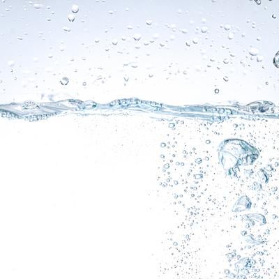透明な水面に落ちる水滴と立ち上がる気泡の写真