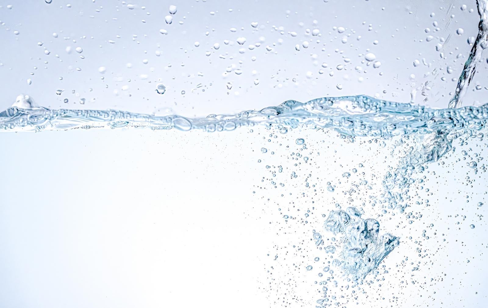 透明な水中に無数の気泡が舞い上がり、右側から水しぶきが流れ込む