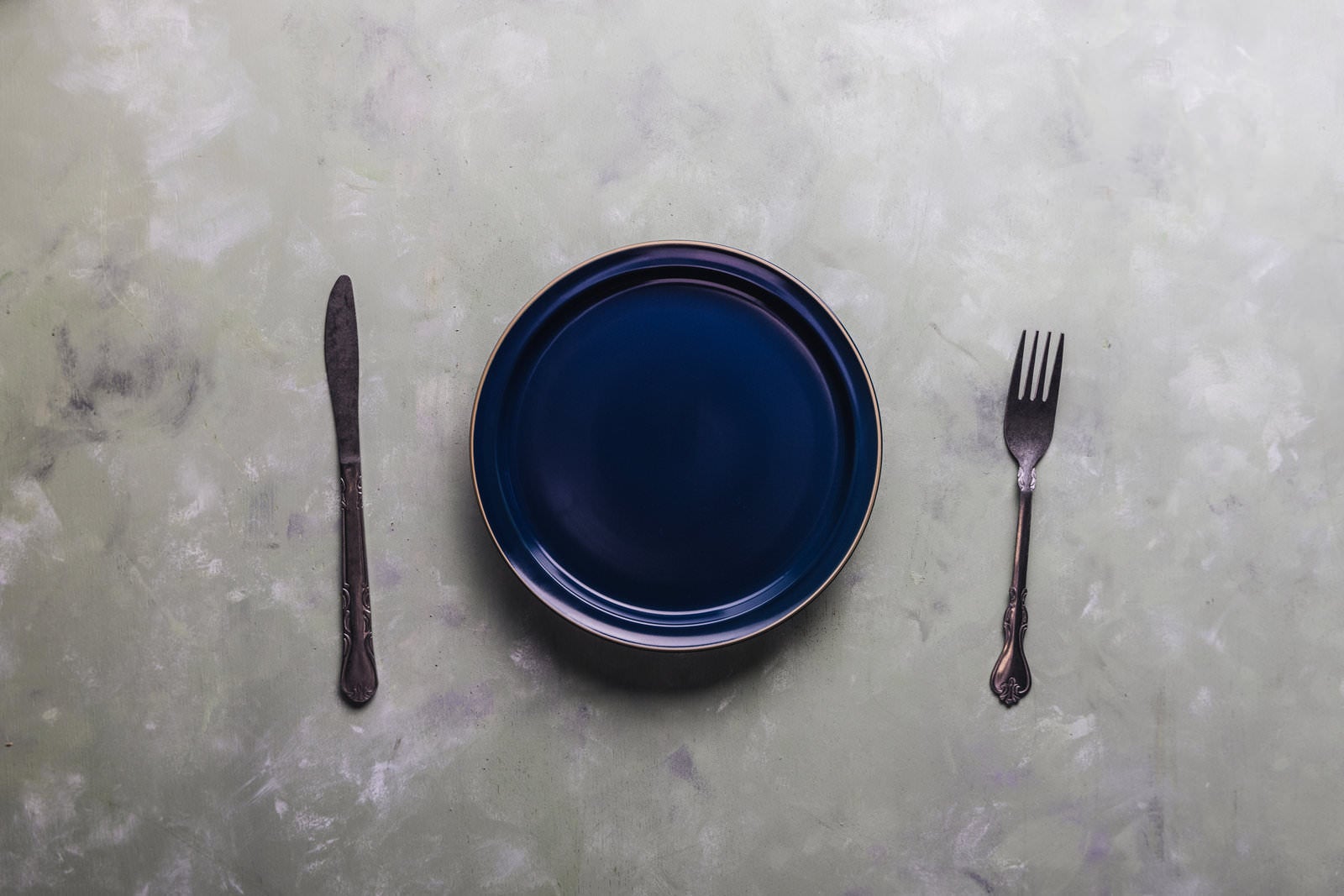 「丸いお皿のサイドに置かれたフォークとナイフ」の写真
