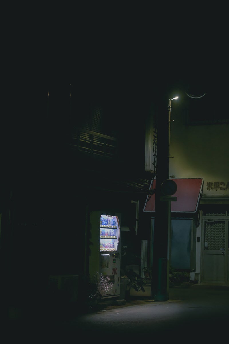 「暗がりに佇む自動販売機」の写真