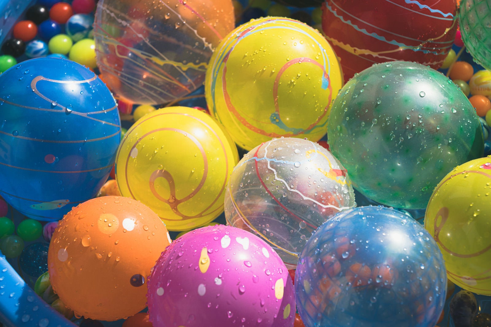 水に浸かった色とりどりの透明なヨーヨーとスーパーボール