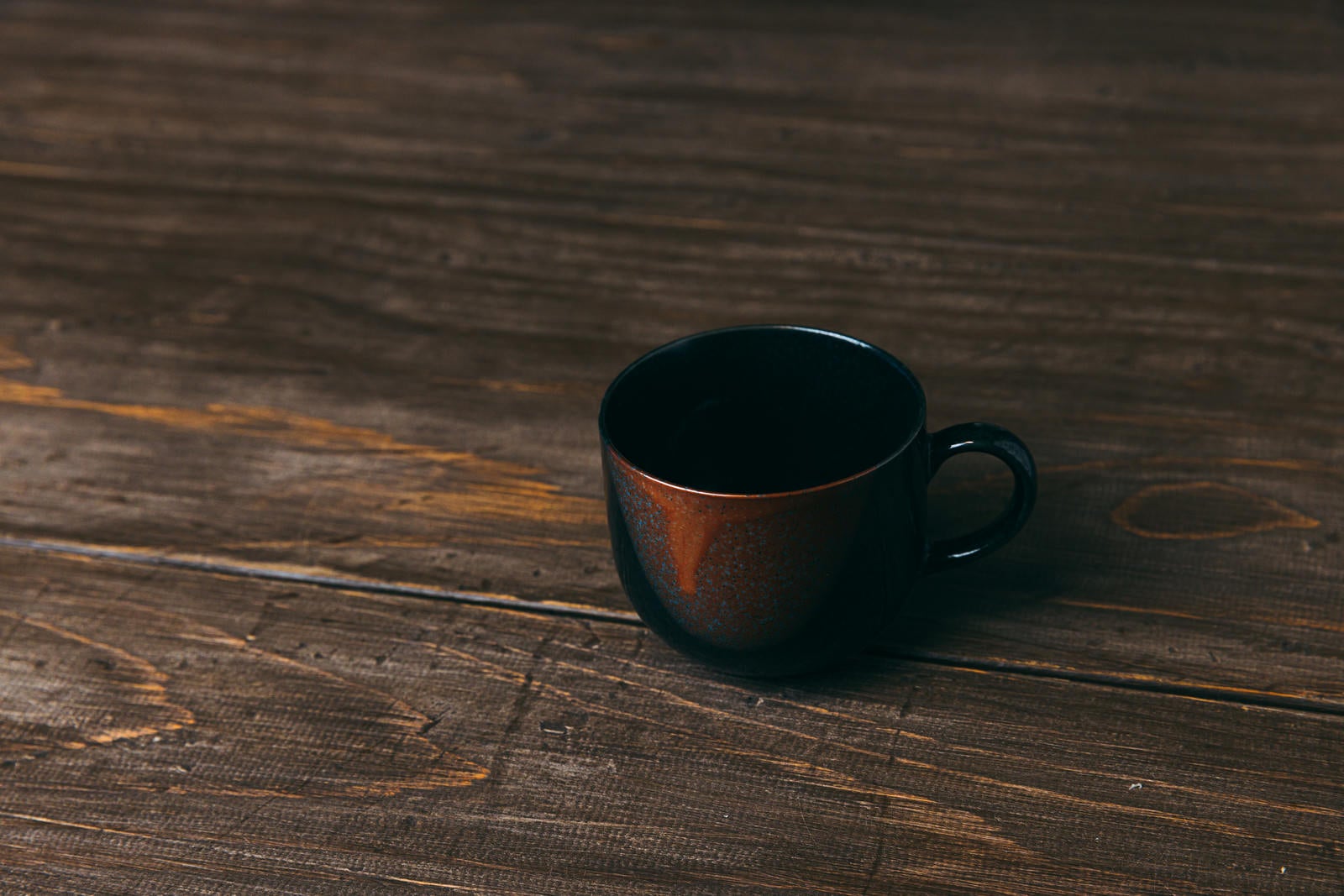 「木目調のテーブルに置かれたコーヒーカップ」の写真