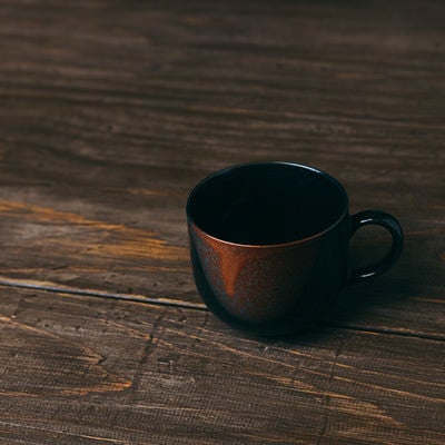 木目調のテーブルに置かれたコーヒーカップの写真