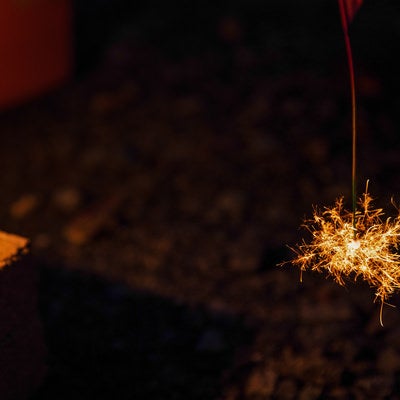 夜間に燃える線香花火の火花が放射状に散る様子の写真