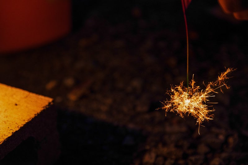 夜間に燃える線香花火の火花が放射状に散る様子の写真
