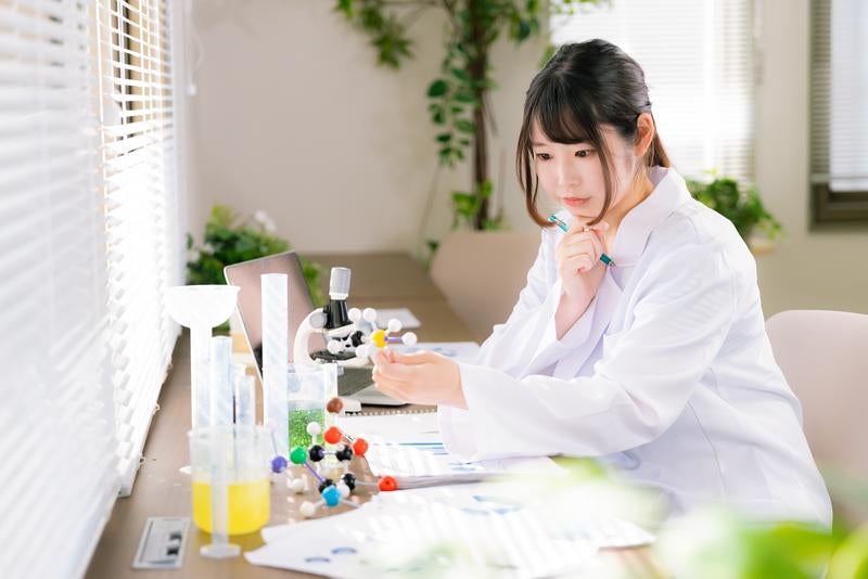 白衣を着た女性が研究室で作業している様子の写真