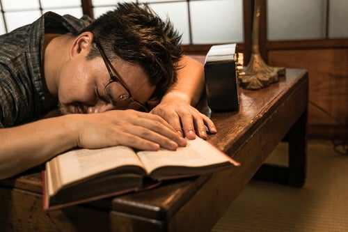 書斎で疲れて寝落ちする男性の写真