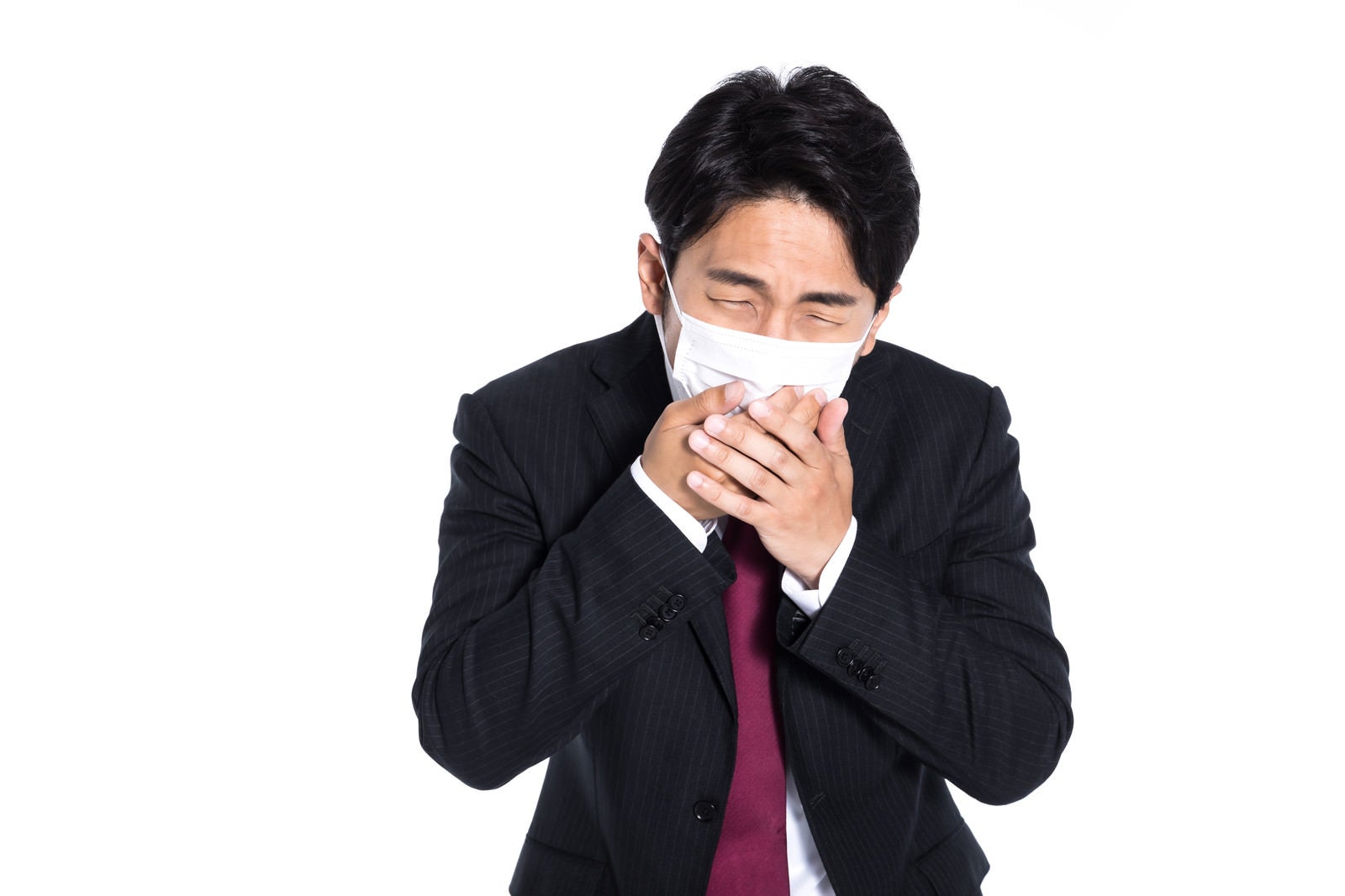 「マスクを両手で押さえて咳を我慢する会社員」の写真［モデル：大川竜弥］