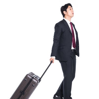 スーツケースを引きずるビジネスマンの写真