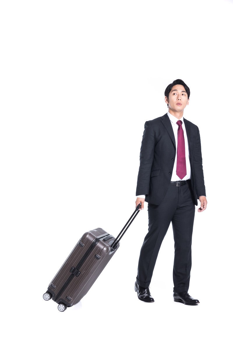 「打ち合わせにスーツケース持参する会社員」の写真［モデル：大川竜弥］