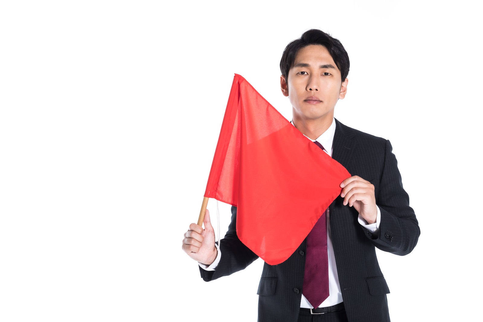 「赤い手旗をもち危険を知らせる会社員」の写真［モデル：大川竜弥］