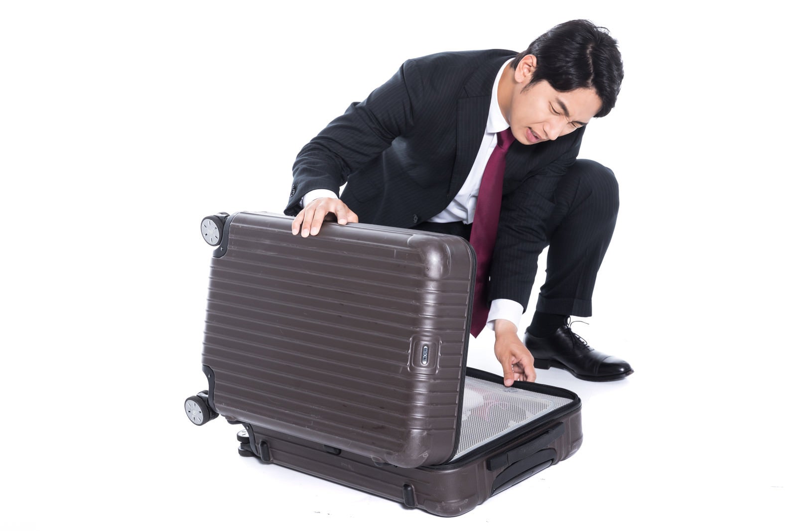 「スーツケースが閉まらないトラブルの会社員」の写真［モデル：大川竜弥］