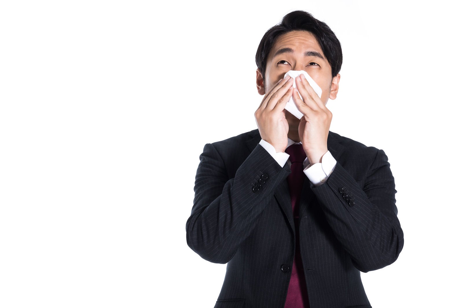 「花粉症で鼻を押さえる会社員」の写真［モデル：大川竜弥］
